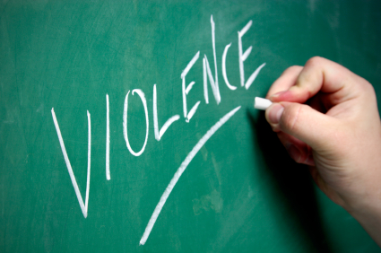 A hand writes the word "Violence" on a chalkboard.